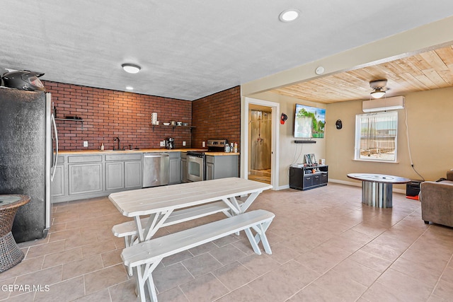 1624 Vinton Rd, Anthony, NM 88021 - kitchen with stainless steel appliances, light tile patterned floors, brick wall, a wall unit AC, and light countertops