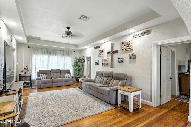 1624 Vinton Rd, Anthony, NM 88021 - living room with a textured wall, a tray ceiling, ceiling fan, wood finished floors, and a wood stove