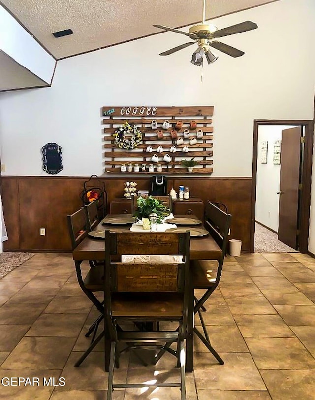 1624 Vinton Rd, Anthony, NM 88021 - tiled dining space featuring a textured ceiling, ceiling fan, wainscoting, and lofted ceiling
