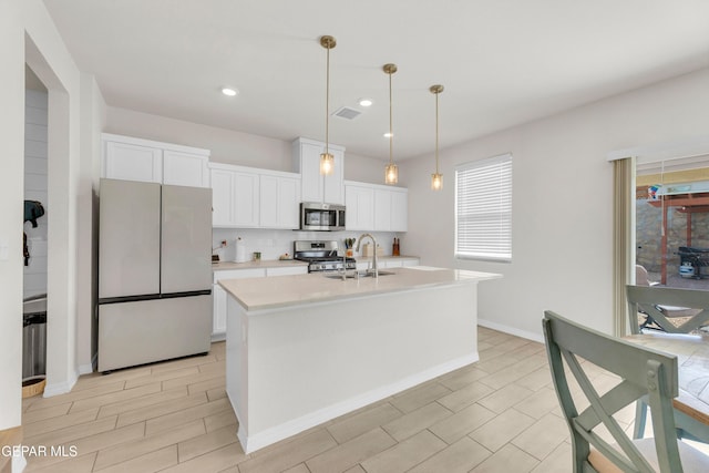 1649 Sam Dominguez, El Paso, TX 79928 - kitchen featuring appliances with stainless steel finishes, light countertops, white cabinetry, decorative light fixtures, and a center island with sink