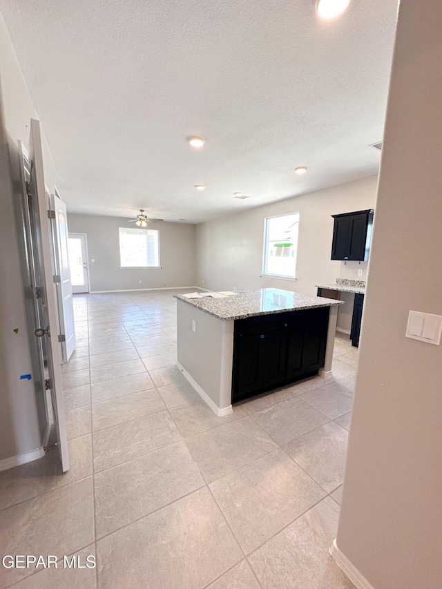 12577 Polo Norte Dr, El Paso, TX 79934 - kitchen featuring dark cabinetry, light tile patterned floors, light stone countertops, recessed lighting, and a textured ceiling