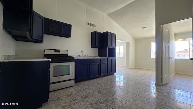 557 Bonampak Dr, San Elizario, TX 79849 - kitchen featuring stainless steel range with gas cooktop, lofted ceiling, light countertops, tile patterned flooring, and blue cabinets