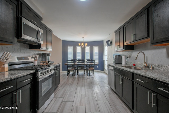 13163 Emerald Isle St, El Paso, TX 79928 - kitchen with appliances with stainless steel finishes, a chandelier, tasteful backsplash, and stone countertops