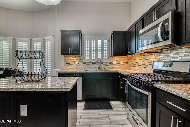 12571 New Dawn Dr, El Paso, TX 79928 - kitchen with stainless steel appliances, tasteful backsplash, a high ceiling, light stone counters, and dark cabinetry