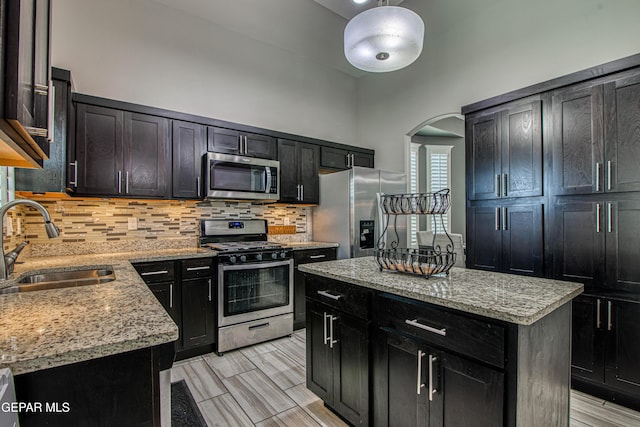 12571 New Dawn Dr, El Paso, TX 79928 - kitchen with stainless steel appliances, arched walkways, decorative backsplash, light stone counters, and a towering ceiling
