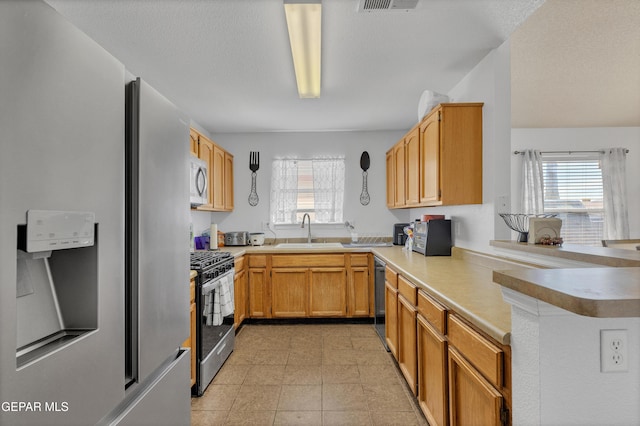 5609 Rick Husband Dr, El Paso, TX 79934 - kitchen with appliances with stainless steel finishes, light countertops, a peninsula, and light tile patterned floors