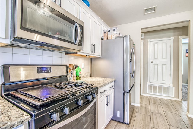 12140 Mesquite Thorn Dr, El Paso, TX 79934 - kitchen with stainless steel appliances, white cabinets, tasteful backsplash, and light stone counters