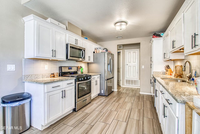 12140 Mesquite Thorn Dr, El Paso, TX 79934 - kitchen with stainless steel appliances, backsplash, white cabinetry, and light stone countertops