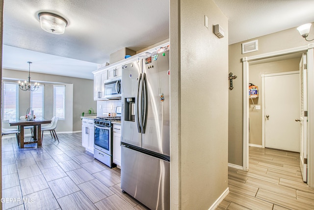 12140 Mesquite Thorn Dr, El Paso, TX 79934 - kitchen featuring stainless steel appliances, white cabinetry, a chandelier, wood finish floors, and light countertops