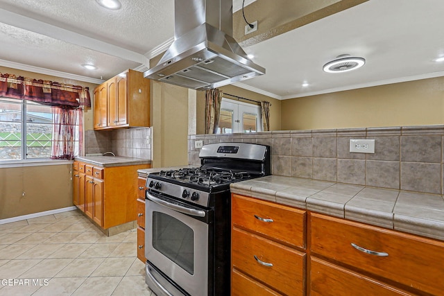 3417 Thomason Ave, El Paso, TX 79904 - kitchen featuring stainless steel range with gas stovetop, range hood, brown cabinetry, light tile patterned flooring, and decorative backsplash
