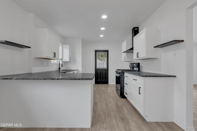 10113 Shenandoah St, El Paso, TX 79924 - kitchen with black gas stove, open shelves, wall chimney exhaust hood, white cabinetry, and dark stone countertops