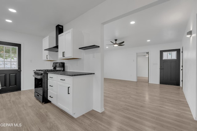10113 Shenandoah St, El Paso, TX 79924 - kitchen featuring gas range oven, wall chimney range hood, ceiling fan, light wood-style flooring, and white cabinetry