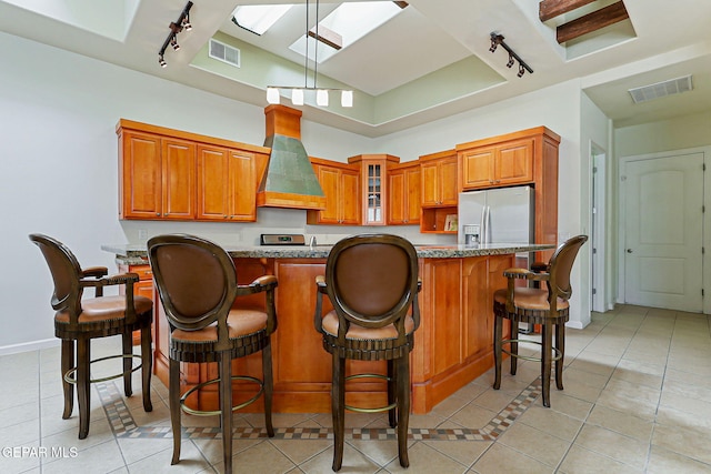 6514 Franklin Cove Place, El Paso, TX 79912 - kitchen featuring track lighting, custom exhaust hood, stainless steel refrigerator with ice dispenser, and light tile patterned floors