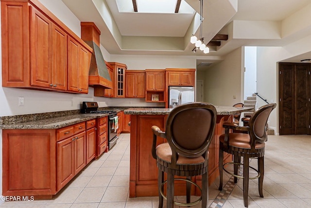 6514 Franklin Cove Place, El Paso, TX 79912 - kitchen with range with gas stovetop, stainless steel fridge with ice dispenser, light tile patterned floors, and brown cabinetry