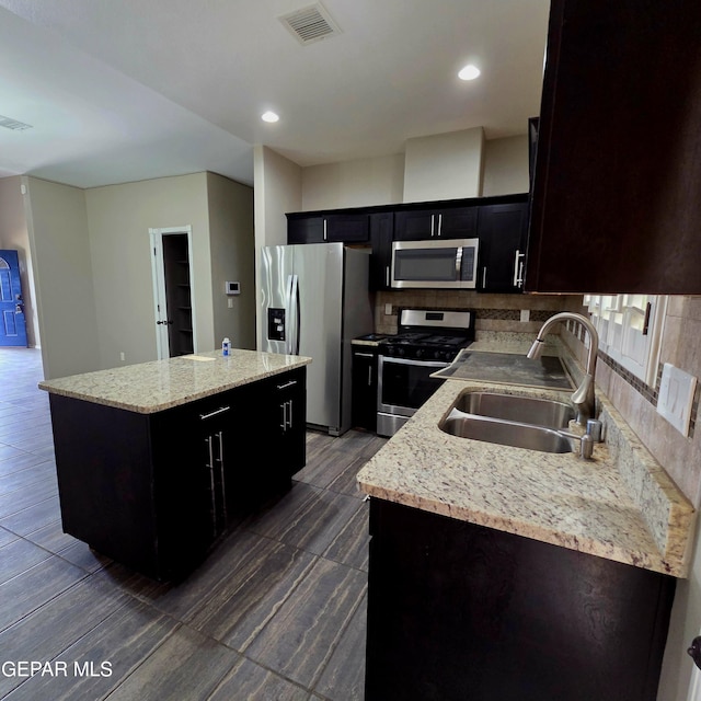 14368 Angel D Garcia Ct, El Paso, TX 79938 - kitchen featuring appliances with stainless steel finishes, a kitchen island, backsplash, recessed lighting, and light stone countertops