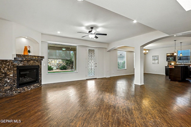 11353 W Ranch Ct, El Paso, TX 79934 - unfurnished living room with arched walkways, a glass covered fireplace, a ceiling fan, dark wood finished floors, and recessed lighting