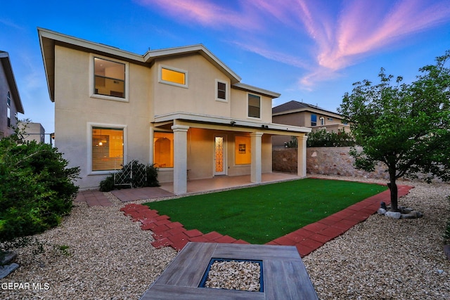 11353 W Ranch Ct, El Paso, TX 79934 - back of property at dusk featuring stucco siding, a lawn, an outdoor fire pit, and a patio