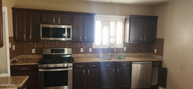 7342 Luz De Villa Ct, El Paso, TX 79912 - kitchen featuring appliances with stainless steel finishes, tasteful backsplash, light stone counters, and dark brown cabinets