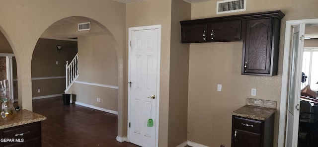 7342 Luz De Villa Ct, El Paso, TX 79912 - kitchen featuring arched walkways, dark wood-style floors, dark brown cabinetry, and light stone counters