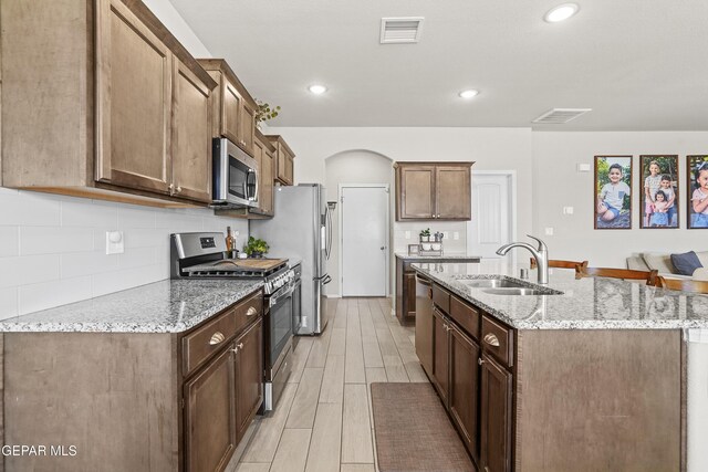 2228 Thawline Pl, El Paso, TX 79911 - kitchen with stainless steel appliances, a kitchen island with sink, tasteful backsplash, light stone countertops, and recessed lighting