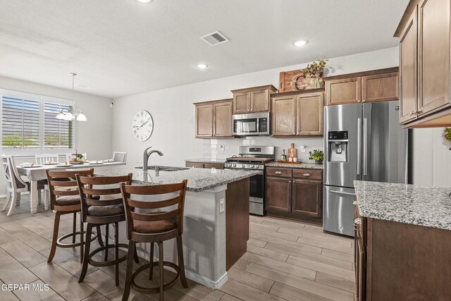 2228 Thawline Pl, El Paso, TX 79911 - kitchen with appliances with stainless steel finishes, light stone counters, a center island with sink, wood tiled floors, and recessed lighting