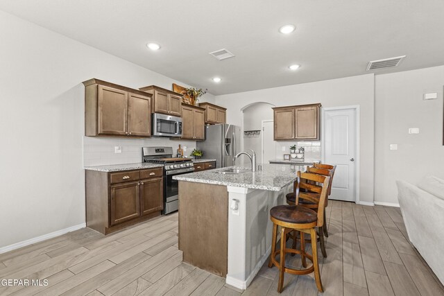 2228 Thawline Pl, El Paso, TX 79911 - kitchen featuring stainless steel appliances, wood tiled floors, a breakfast bar, arched walkways, and recessed lighting