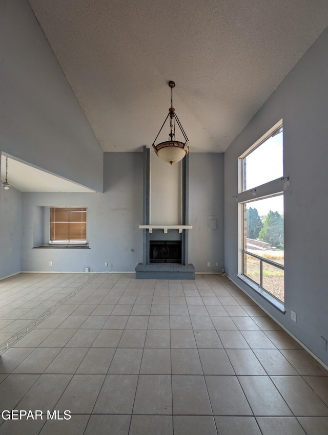11828 Tracy Austin Ln, El Paso, TX 79936 - unfurnished living room featuring high vaulted ceiling, tile patterned floors, a fireplace with raised hearth, and a textured ceiling