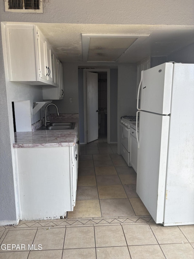 11828 Tracy Austin Ln, El Paso, TX 79936 - kitchen featuring white appliances, white cabinets, light tile patterned floors, and light countertops