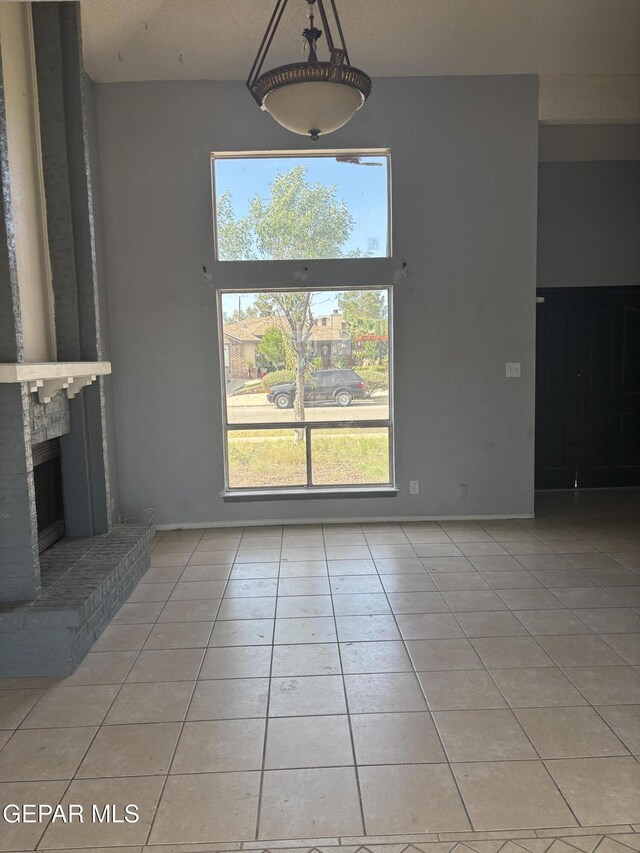 11828 Tracy Austin Ln, El Paso, TX 79936 - unfurnished dining area featuring light tile patterned floors, a high ceiling, and a fireplace