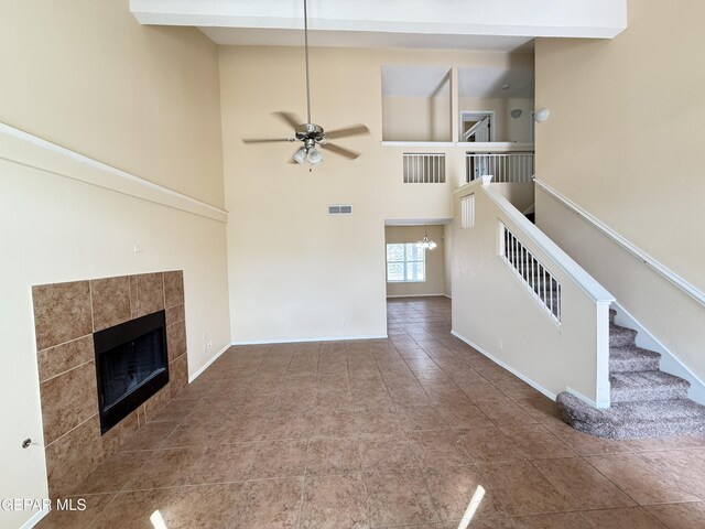 11025 Acoma St, El Paso, TX 79934 - unfurnished living room with a tile fireplace, tile patterned flooring, a ceiling fan, a high ceiling, and a chandelier