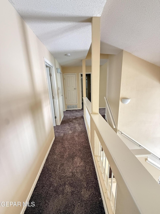 11025 Acoma St, El Paso, TX 79934 - hall featuring dark carpet, a textured ceiling, and an upstairs landing