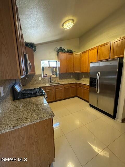 1718 Challenger Ln, El Paso, TX 79936 - kitchen featuring appliances with stainless steel finishes, brown cabinets, backsplash, light tile patterned floors, and light stone counters