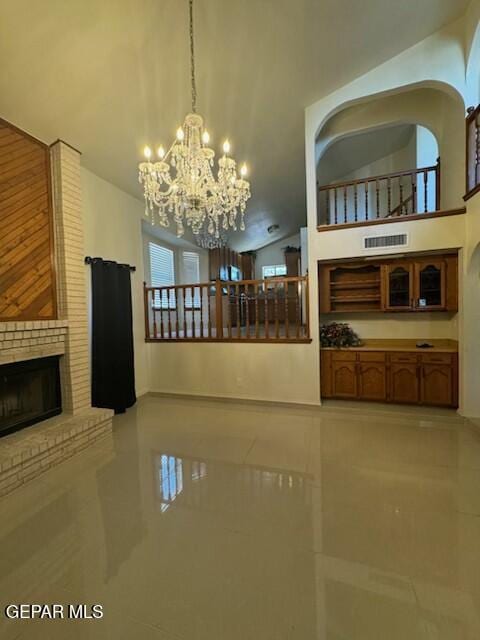 1718 Challenger Ln, El Paso, TX 79936 - unfurnished living room featuring a chandelier, light tile patterned flooring, a fireplace, and a towering ceiling