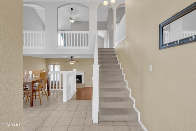 4328 Loma Alegre Dr, El Paso, TX 79934 - stairs with ceiling fan, tile patterned flooring, a high ceiling, a fireplace with raised hearth, and a textured wall