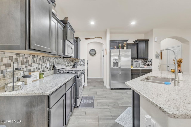 237 Gonzalo Cir, El Paso, TX 79932 - kitchen with stainless steel appliances, arched walkways, decorative backsplash, light stone counters, and recessed lighting