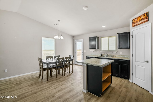 14207 Desierto Bonito St, Horizon City, TX 79928 - kitchen featuring lofted ceiling, light countertops, dark cabinets, a chandelier, and light wood-style flooring