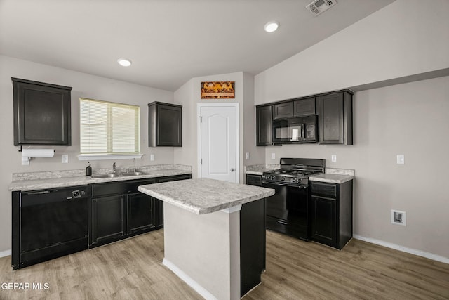 14207 Desierto Bonito St, Horizon City, TX 79928 - kitchen featuring black appliances, light wood-type flooring, light countertops, a kitchen island, and dark cabinetry