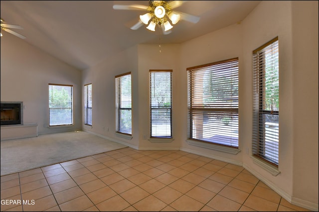 712 Rena Mae Ct, Las Cruces, NM 88005 - unfurnished living room featuring a ceiling fan, light colored carpet, vaulted ceiling, light tile patterned floors, and a glass covered fireplace