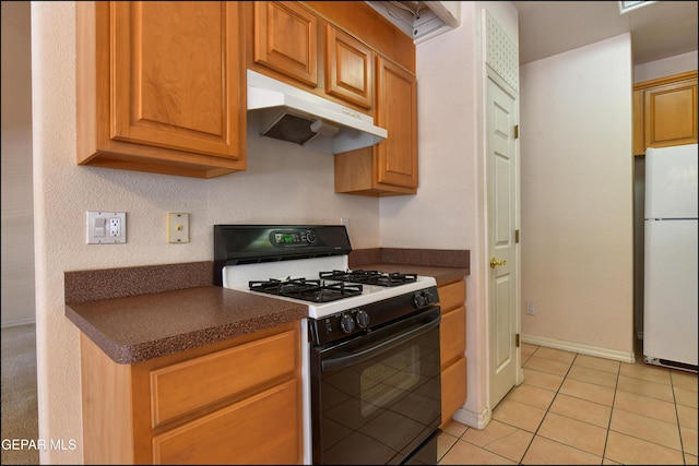 712 Rena Mae Ct, Las Cruces, NM 88005 - kitchen featuring range with gas stovetop, freestanding refrigerator, under cabinet range hood, and dark countertops
