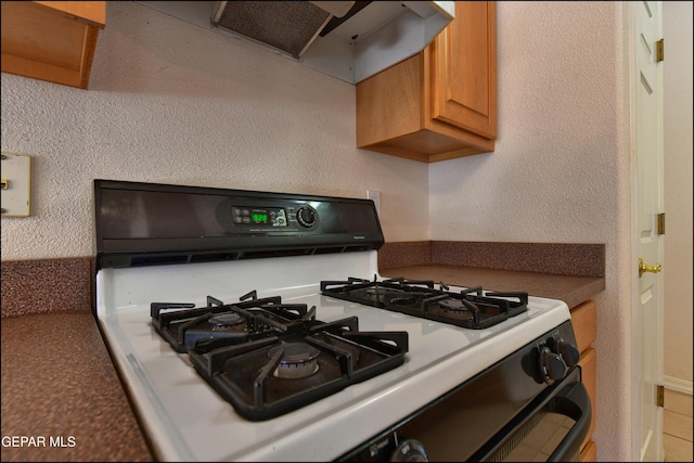 712 Rena Mae Ct, Las Cruces, NM 88005 - kitchen featuring white gas range, range hood, brown cabinets, and dark countertops