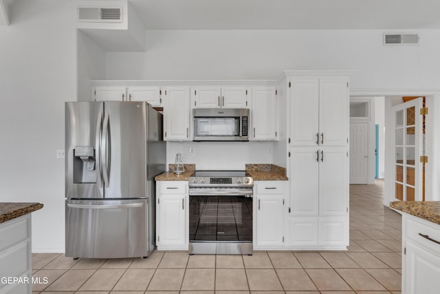 1121 Regal Ridge Dr, El Paso, TX 79912 - kitchen with appliances with stainless steel finishes, light tile patterned flooring, white cabinets, and dark stone counters