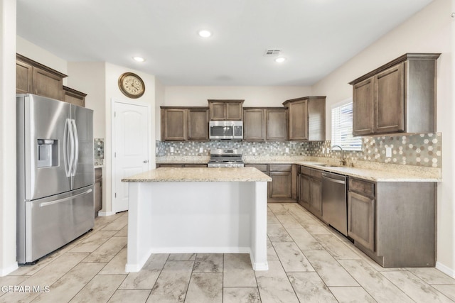 541 Sunset Valley Ave, Socorro, TX 79927 - kitchen with stainless steel appliances, a center island, light stone countertops, decorative backsplash, and recessed lighting