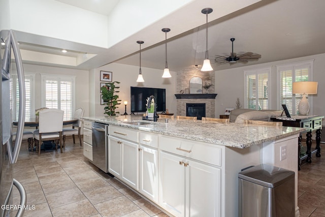 7317 Kiowa Creek Dr, El Paso, TX 79911 - kitchen featuring a ceiling fan, a fireplace, stainless steel appliances, open floor plan, and white cabinetry