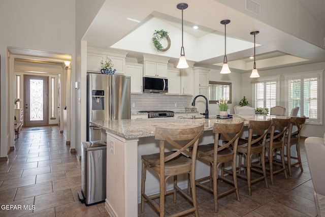 7317 Kiowa Creek Dr, El Paso, TX 79911 - kitchen featuring appliances with stainless steel finishes, backsplash, a breakfast bar, and light stone counters
