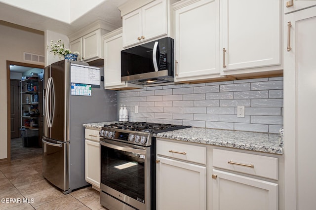 7317 Kiowa Creek Dr, El Paso, TX 79911 - kitchen with stainless steel appliances, tasteful backsplash, light tile patterned flooring, light stone countertops, and white cabinetry