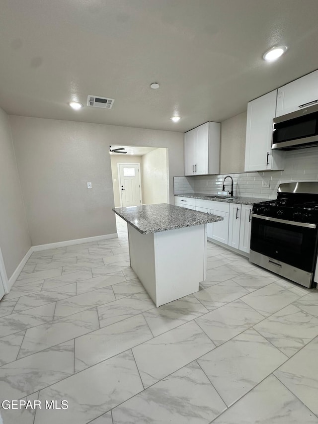 7216 Amethyst Rd, El Paso, TX 79915 - kitchen featuring stainless steel appliances, light stone countertops, a kitchen island, light marble finish flooring, and backsplash
