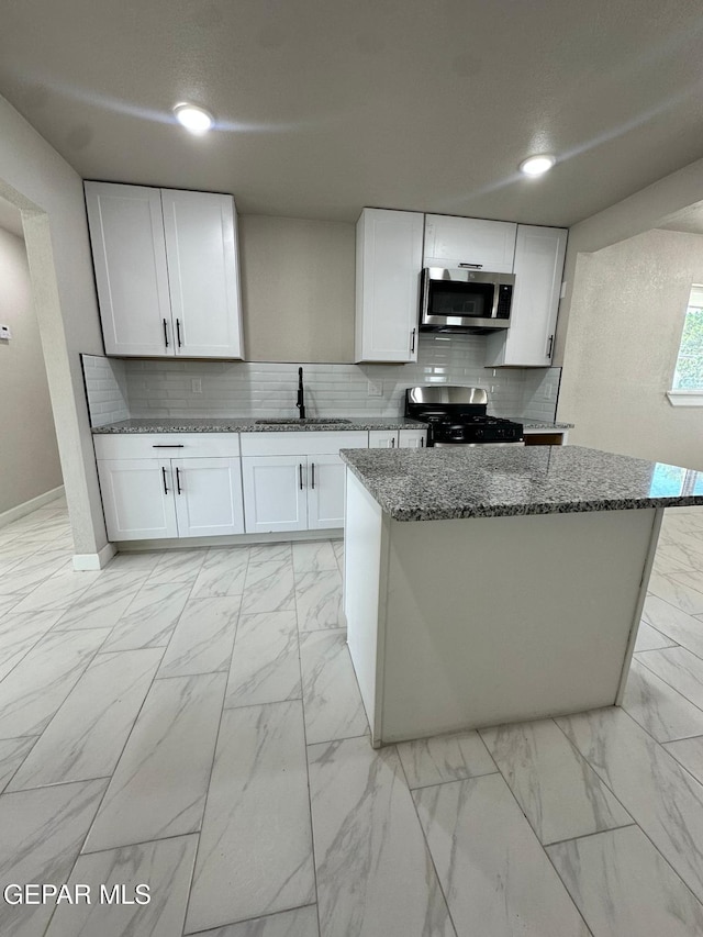 7216 Amethyst Rd, El Paso, TX 79915 - kitchen featuring gas stove, stainless steel microwave, light marble finish flooring, dark stone counters, and decorative backsplash