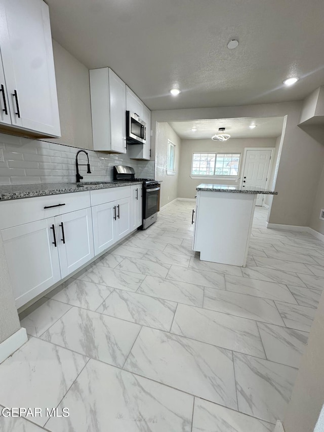 7216 Amethyst Rd, El Paso, TX 79915 - kitchen featuring stainless steel appliances, light marble finish flooring, stone counters, white cabinets, and recessed lighting