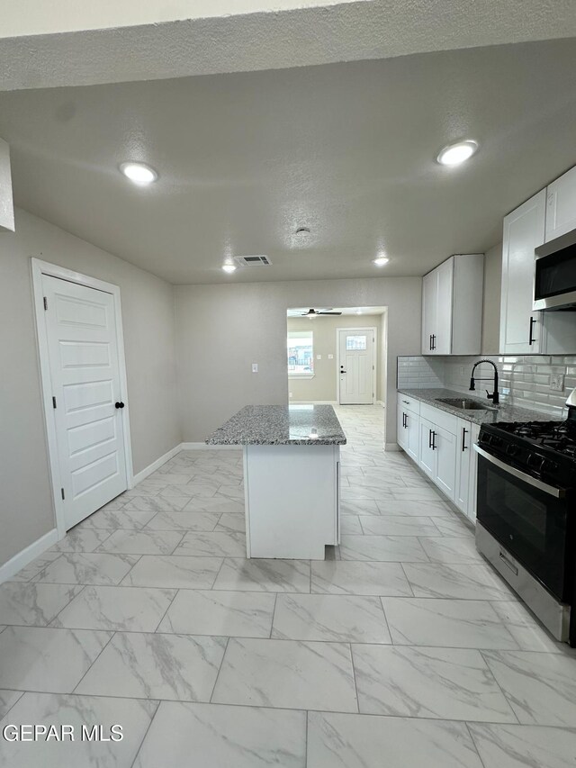7216 Amethyst Rd, El Paso, TX 79915 - kitchen featuring stainless steel appliances, a center island, light marble finish flooring, light stone counters, and recessed lighting