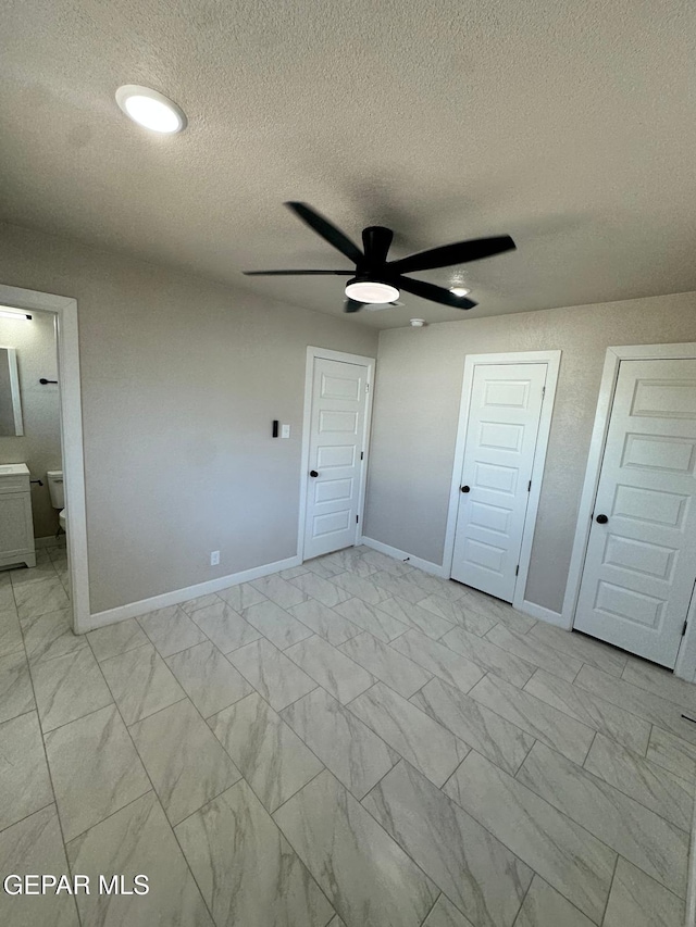 7216 Amethyst Rd, El Paso, TX 79915 - unfurnished bedroom with light marble finish floors, a textured ceiling, and connected bathroom